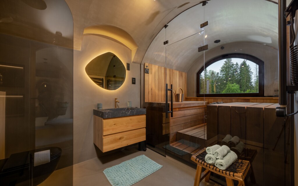 Revonia underground sauna interior – wood-paneled vault with arched window, bathtub and bathroom in earth-sheltered wellness retreat