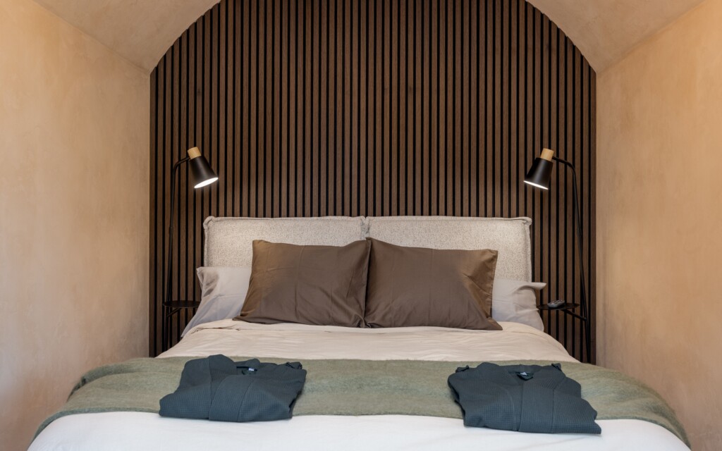 Revonia underground house luxury bedroom – double bed with wooden slat feature wall under arched vault ceiling in modular earth home